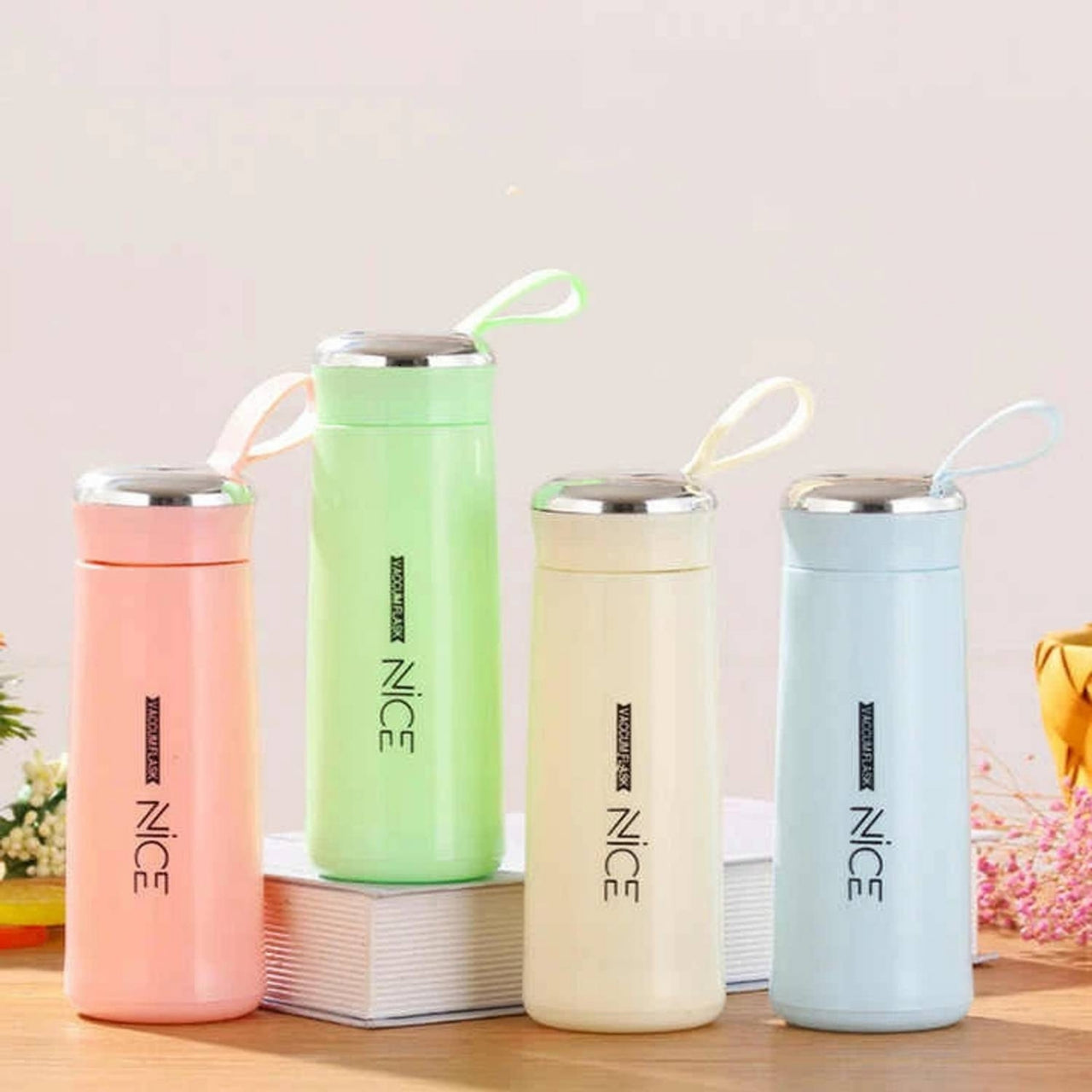 Four colorful thermos bottles with 'NICE' branding on a wooden surface.