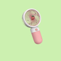 Pink handheld fan with strawberry design on a light green background