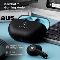 Black earbuds with charging case on a desk with computer equipment in the background
